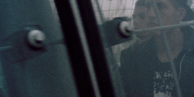 Adolescent en casquette derrière un grillage, tourné en pellicule 16 mm – pub Bundesliga Stiftung