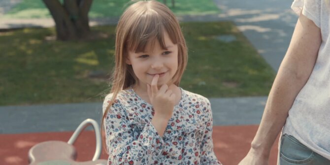 Petite fille en robe fleurie souriant timidement dans un parc – pub Candia Les laitiers responsables
