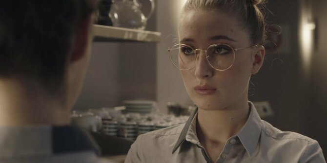 Jeune femme à lunettes, cheveux attachés, dans une cuisine de restaurant – série Ici tout commence