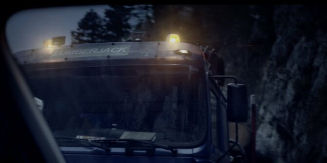 Cabine de camion forestier avec gyrophares orange sur une route de forêt sombre – pub Volkswagen